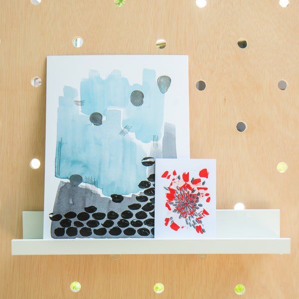 a small art print and large art print on a picture ledge