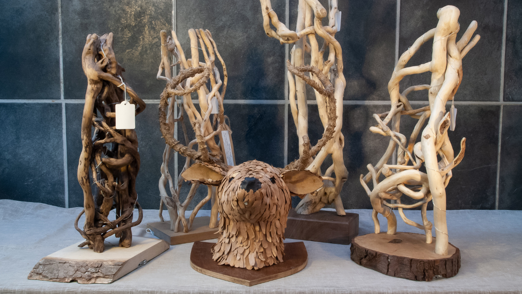 Wood work by Jill including several lamps made from knarled twigs and sticks and a deer made from wood shavings in the centre</em>