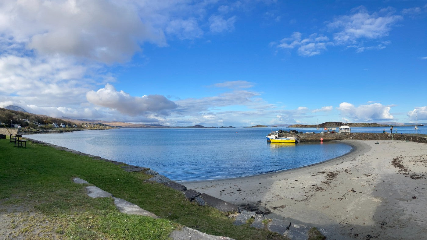 Bright blue sea and yellow boat off-shore in Craighouse, Jura