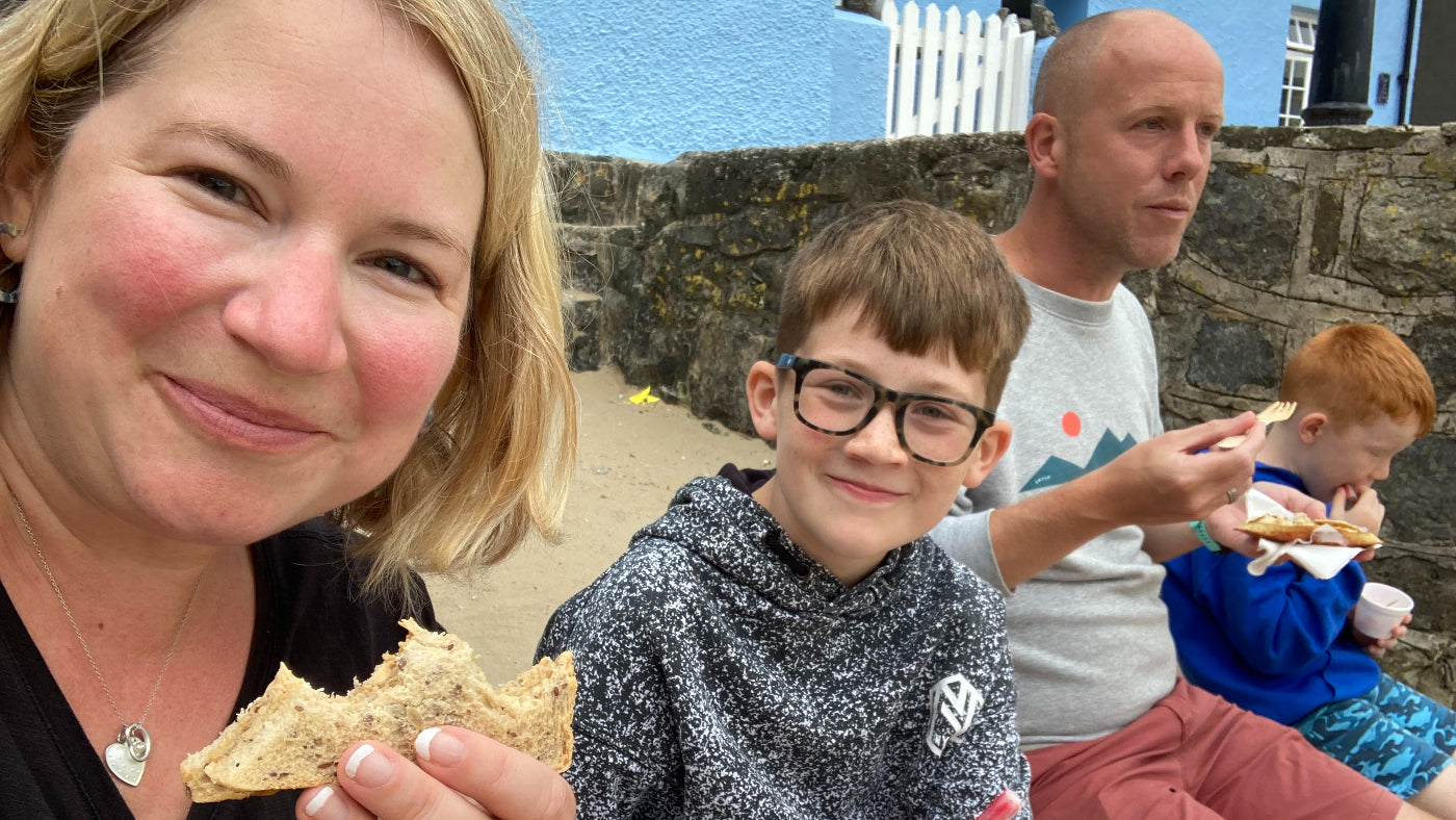 Soph with her son and family eating crab sarnie on a beach front - landscape crop