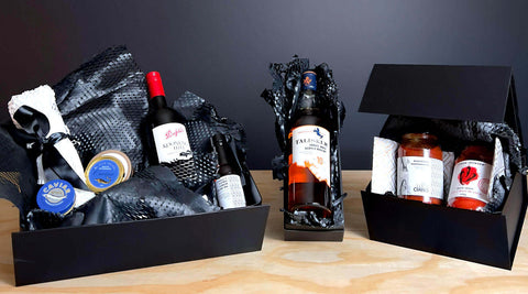 black gift boxes with jars of jam and bottles of wine