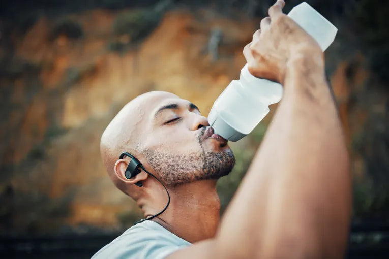 man staying hydrated whilst outside drinking water from a sports bottle 