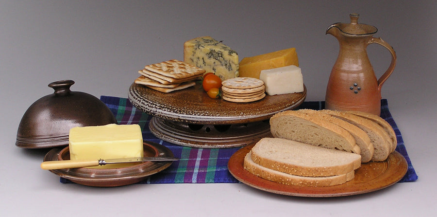 Large blue/black butter dish, elevated cheese platter, pale vinaigrette and side plate