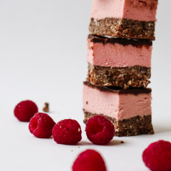 Stack of Trove Desserts famous hand made Raspberry Nanaimo Bars with fresh raspberries surrounding