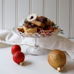 Trove Desserts Chrismas Dessert display with crystal cake stand filled with handmade seasonal desserts from Trove and a linen white napkin and Christmas glitter red and gold bobbles