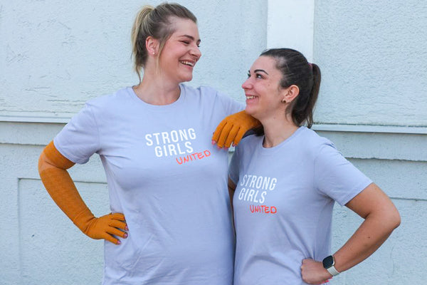 Caroline und Vanessa tragen das Strong Girls United T-Shirt-Kleid und sehen sich an