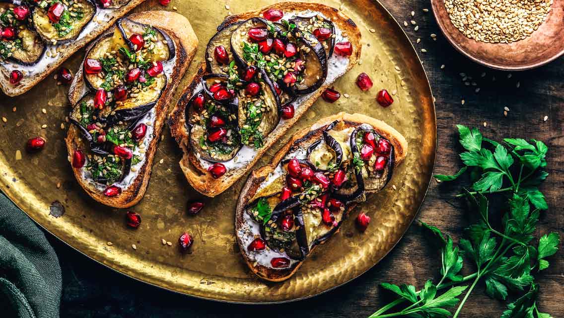 Auberginen-Bruschetta mit Minz-Joghurt, Kräuteröl und Granatapfel