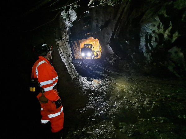 a miner wearing an orange hi-vis suit working underground to show how sustainable mining can help local communities