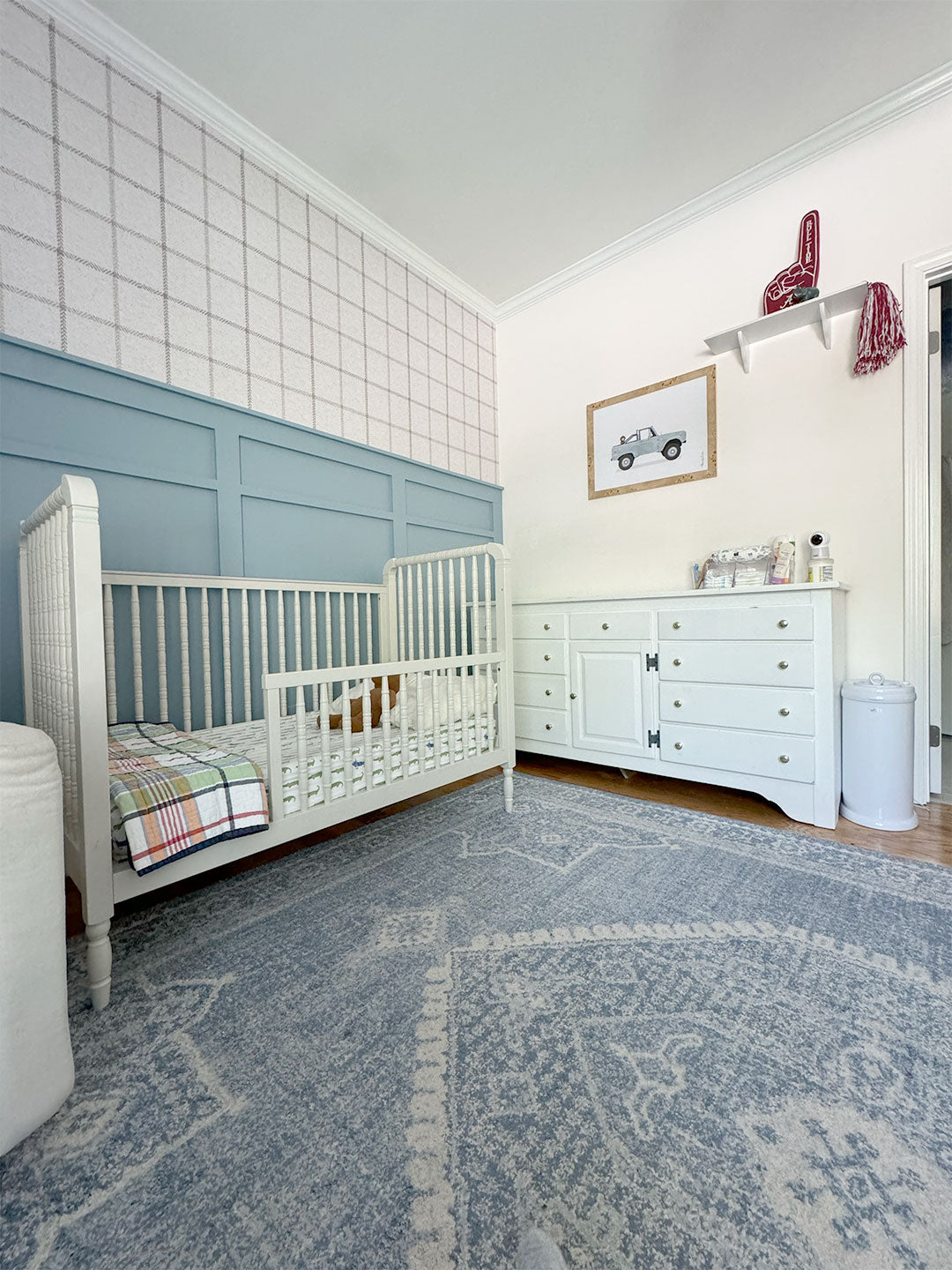 A boy's nursery featuring plaid wallpaper with blue accents throughout the room, creating a cozy and stylish environment.