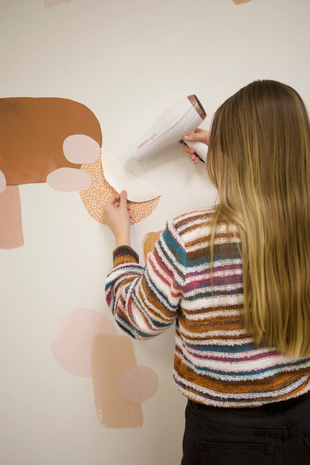 woman removing wall decals safely with hair dryer