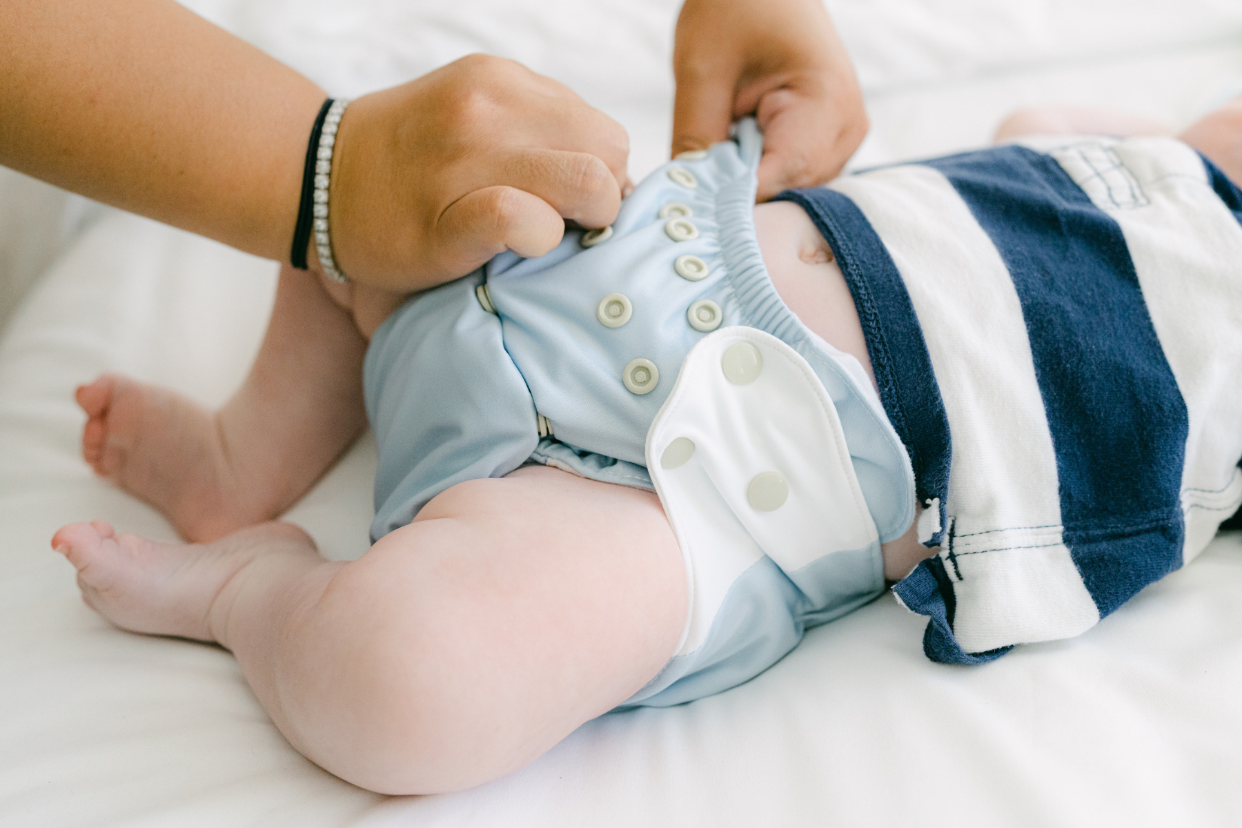 Image of a baby with cloth diaper being fastened by parent