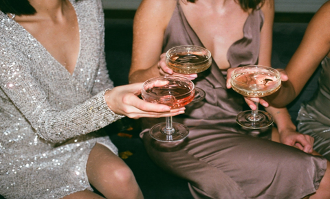 Women sitting at a bar holding cocktails