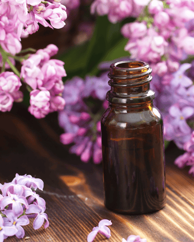 an opened essential oil bottle surrounded by purple flowers