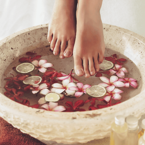 a female feet dip inside a massage bowl with flowers petal 