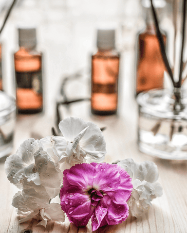 white and pink flowers, three essential oil bottles and a reed diffuser bottle