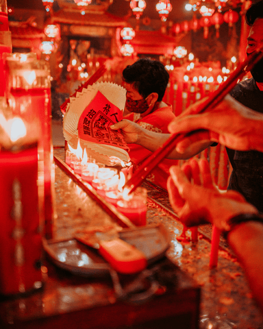 people burning incense and paper inside the temple