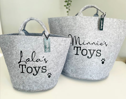 A pair of grey personalised dog toy storage baskets with a Pooch label tag