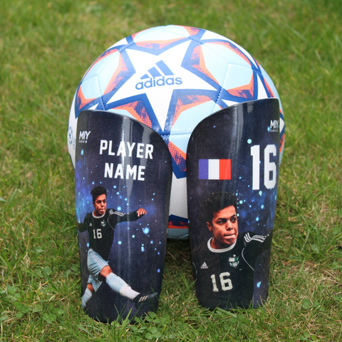 Pair of personalised football shin guards against a football