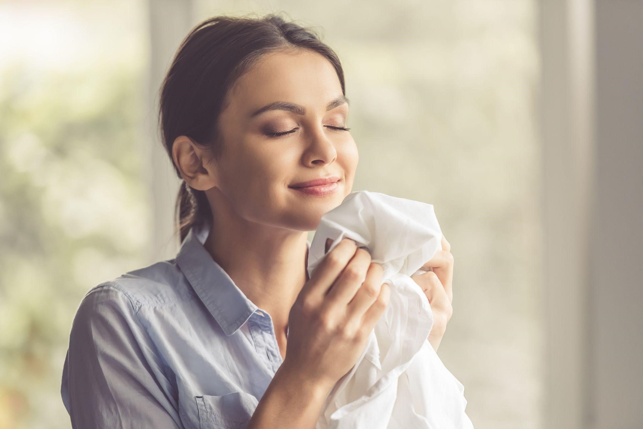 A person smelling a freshly washed cloth with a blurred background