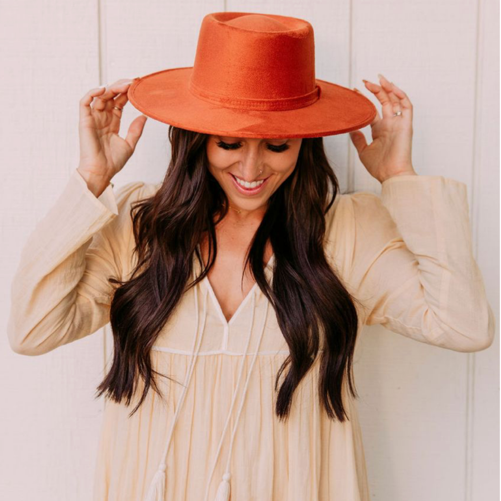 A model wears a copper boater-style hat that is suede