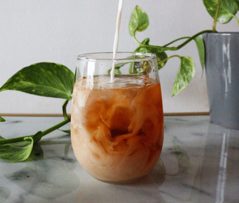 A glass of iced tea with cream pouring in to create a swirl effect