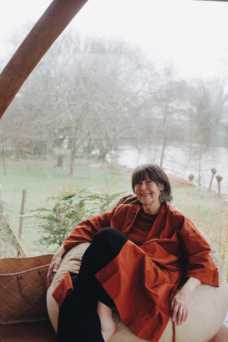 Pip in rust coloured house kimono lounging on beanbag smiling