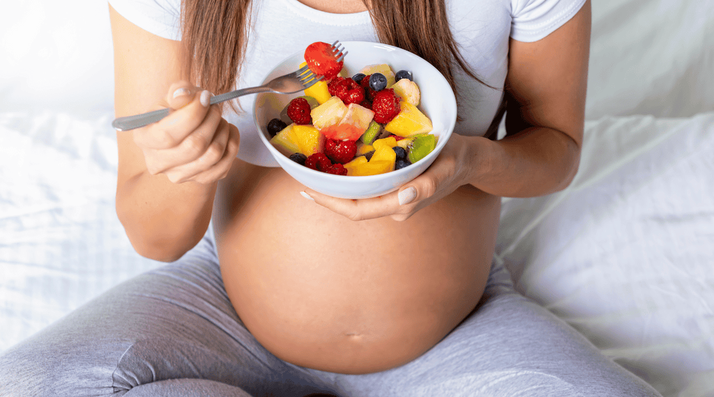 Preparing for Pregnancy with Psoriasis - pregnant woman eats a bowl of tasty fresh fruit.