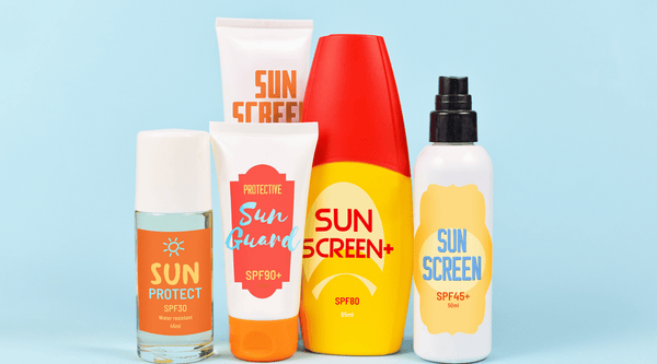 Breastfeeding and Psoriasis - different protective sun screen bottles and tubes that have made up labels, all saying sun protect or sun screen. Standing against a light blue background.