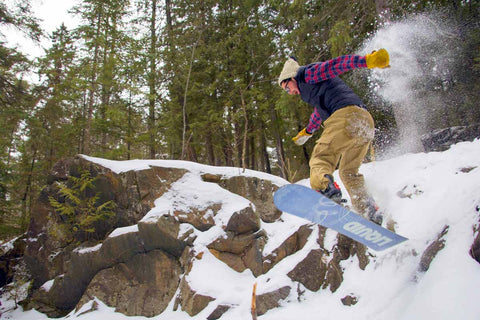 Person doing a jump off a ridge on a freeride snowboard