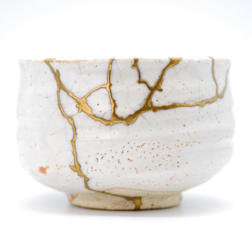 Explore our collection of Kintsugi tea bowls. This white bowl features elegant gold repairs in the wabi-sabi style.