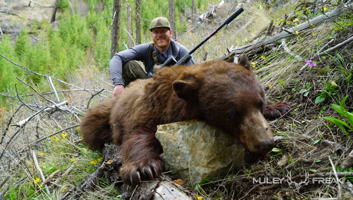Erik Van Woerkom sitting next to a big black bear that he shot in the idaho backcountry