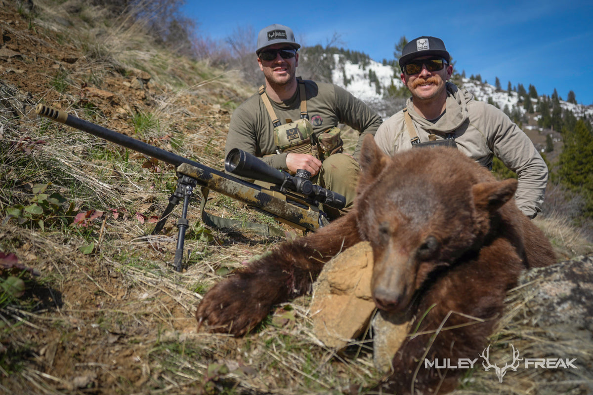 Aaron Van Woerkom sitting beside a cinnamon colored black bear that he shot in Idaho with a rifle