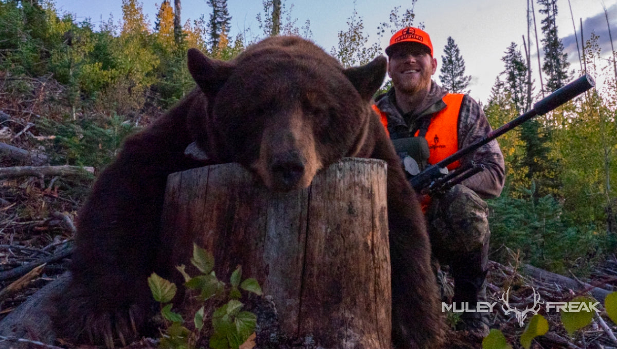 Erik Van Woerkom sitting next to a big fall black bear that he harvested after it was eating on his elk carcass