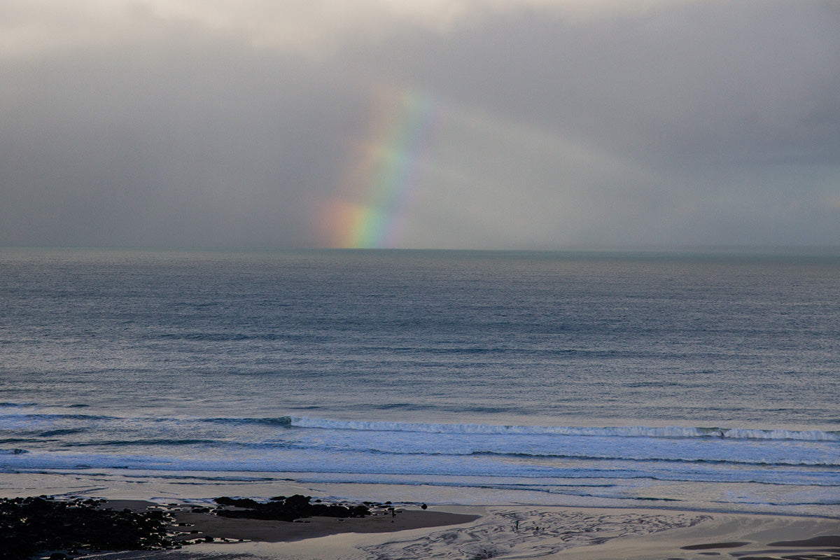 rainbow at dusk over waves and the beach