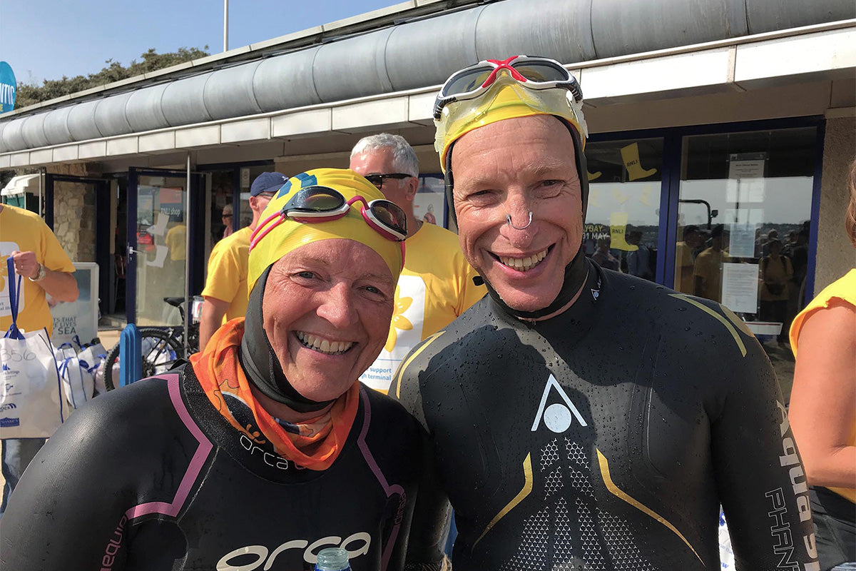 sea swimmers wearing yellow hats, goggles and wetsuits, smiling 