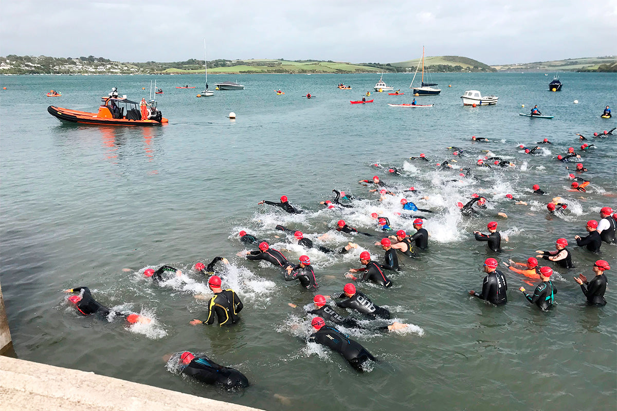 swimmers in the water wearing wetsuits 