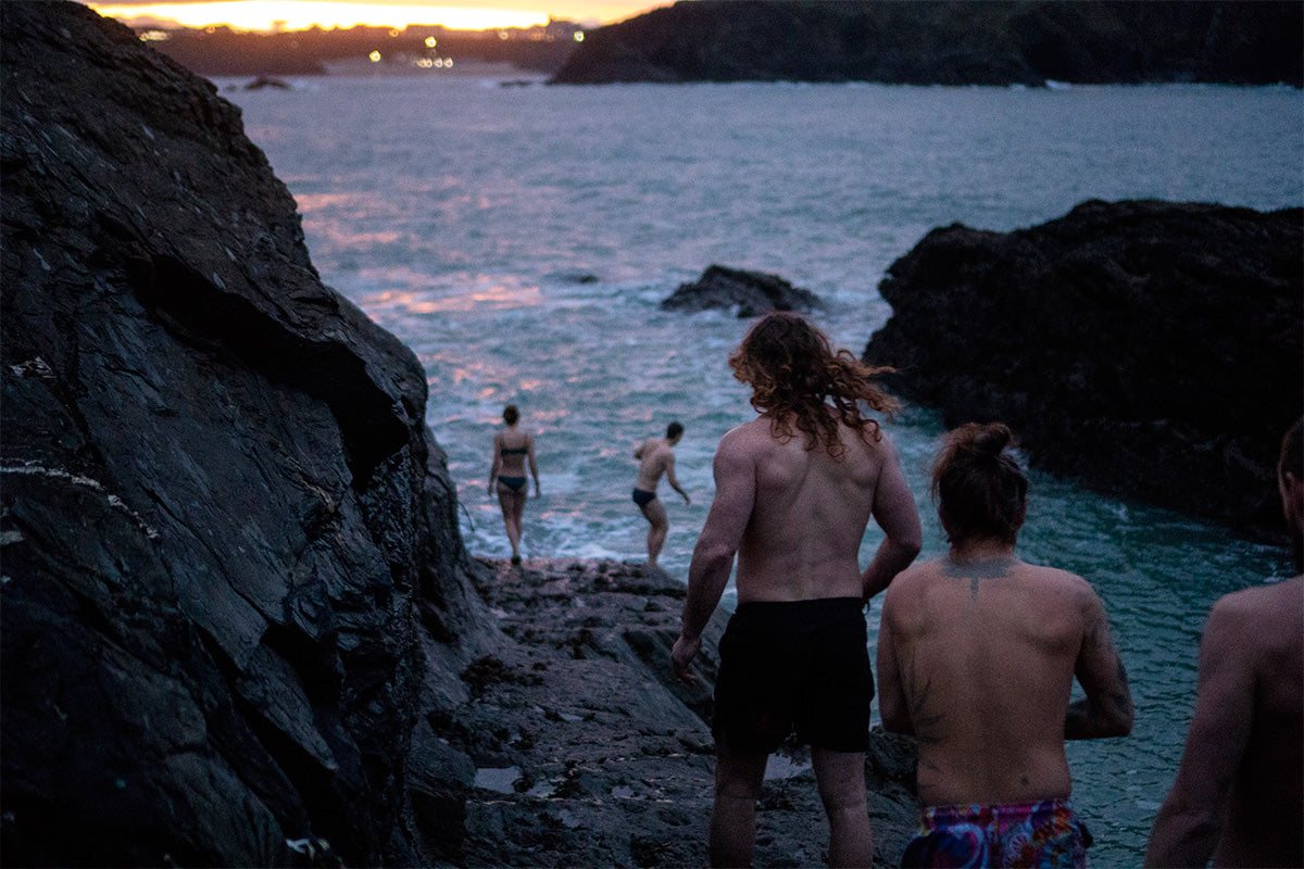 group of friends walk down to the waters edge at sunrise for a swim