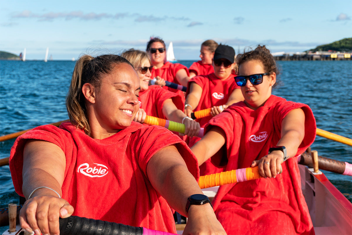 women rowing wearing red robies 
