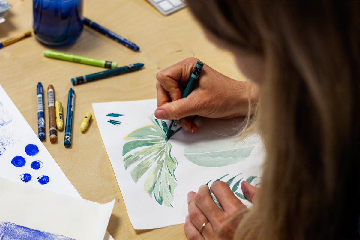 woman painting abstract leaves in green on white paper 