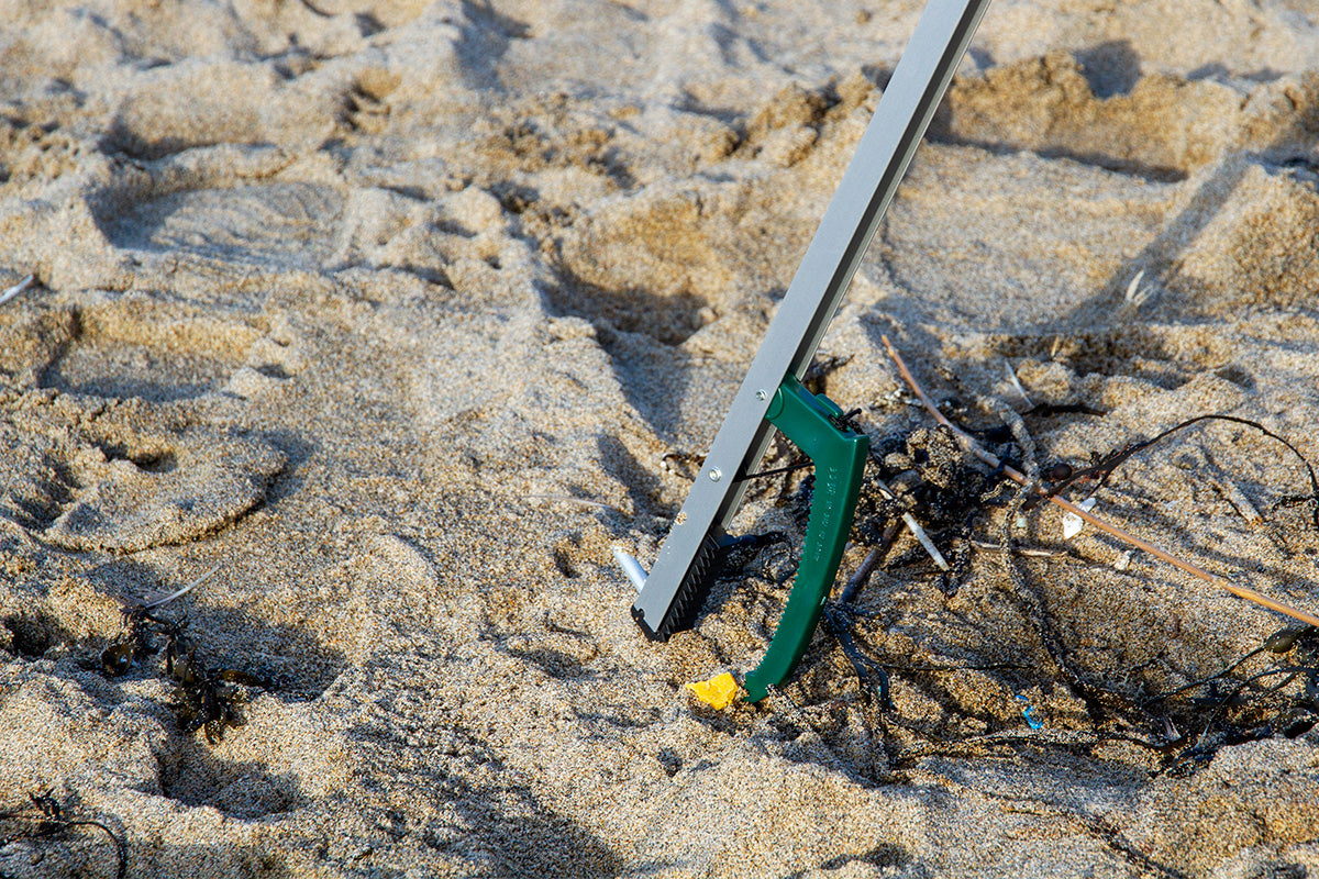 Litter picking near micro-plastic on sand strewn with seaweed