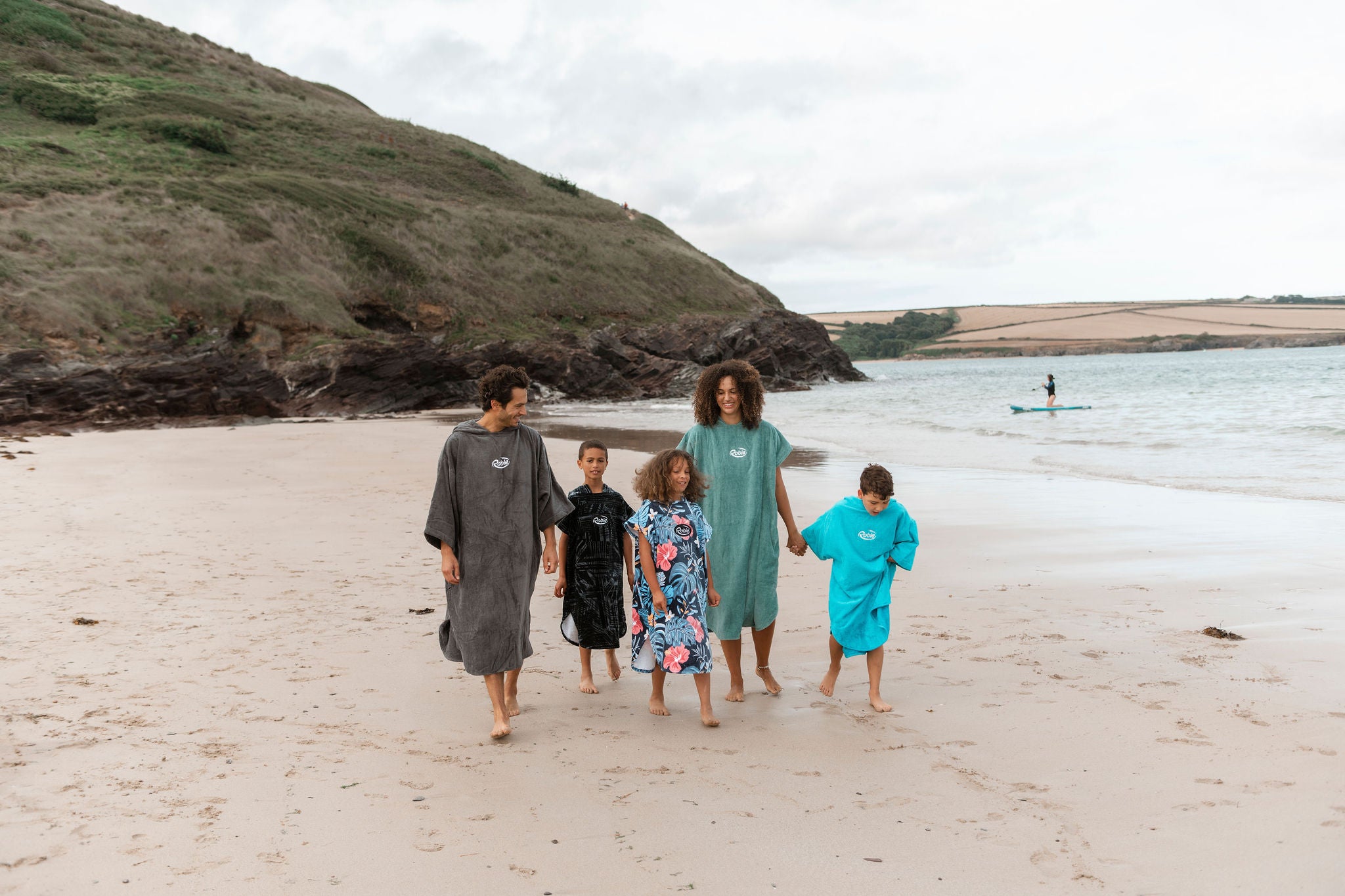 family in towelling robes walking on the beach