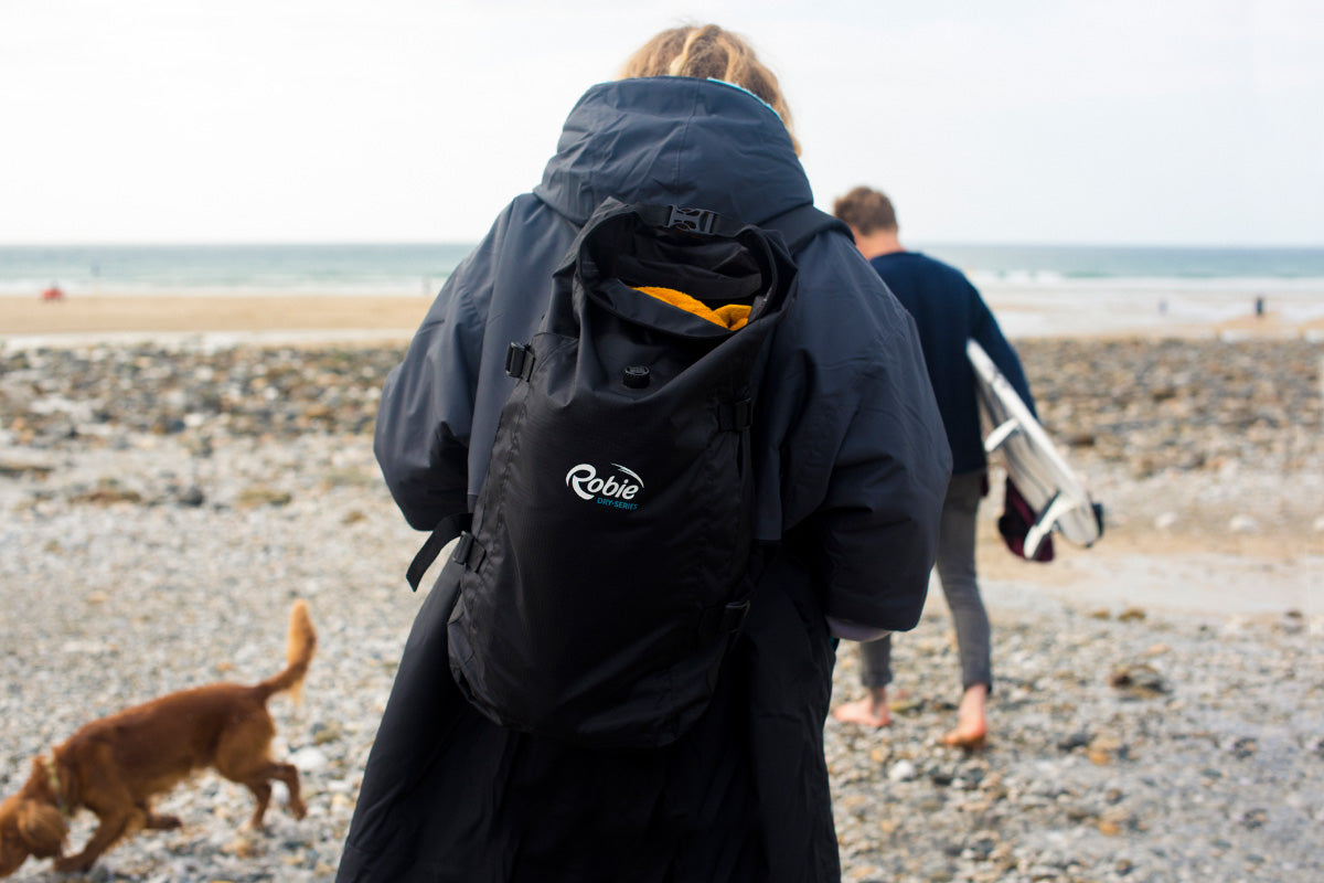 girl with backpack on walks away from camera down to the sea