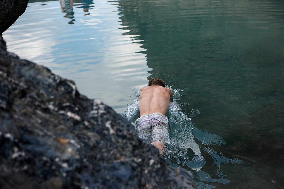 Man in board shorts diving into a tidal pool