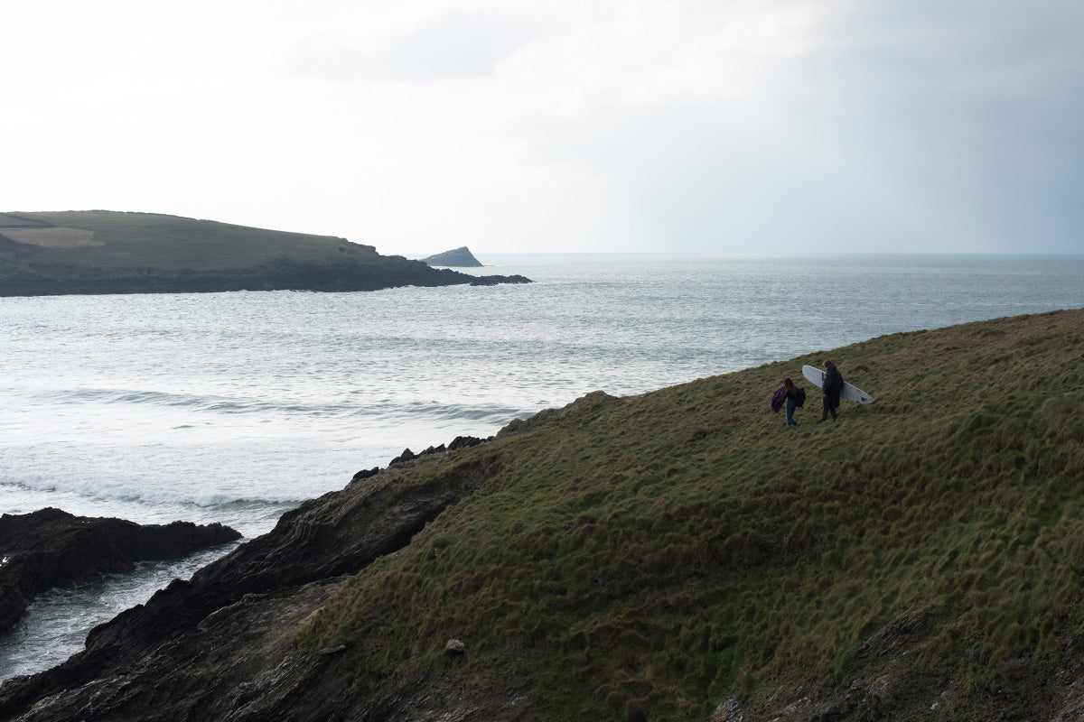 couple walk to the sea holding surfboard 