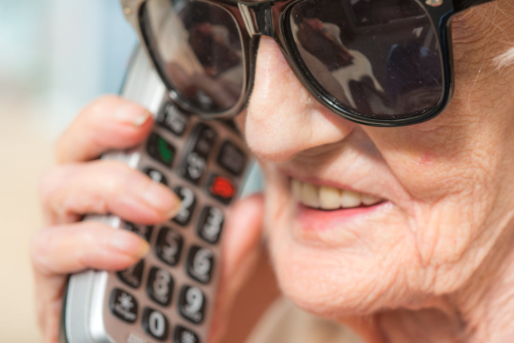 an elderly woman smiling while talking with someone using her cordless phone