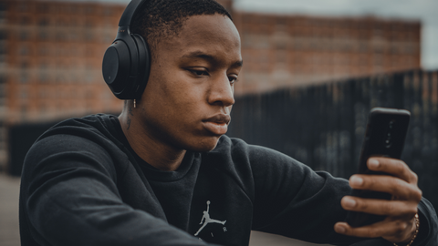 young black man wearing headphones while scrolling on phone