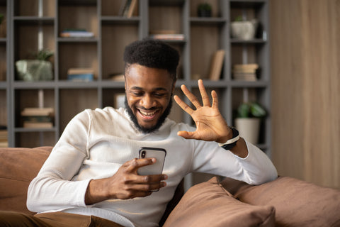 black man waving hello to phone on FaceTime video call