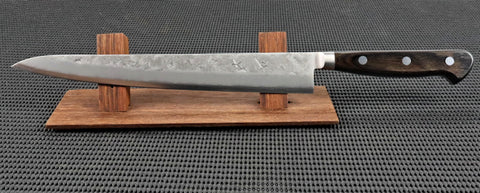 Ohishi Ginsan Handmade 240mm Sujihiki (Slicer) Japanese Kitchen Knife with a Nashiji (Pear skin) finish and a mahogany handle on a red wood stand