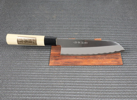 White Steel Teruhide Santoku(General Purpose) Japanese Kitchen Knife with Traditional natural wood handle on a red wood stand