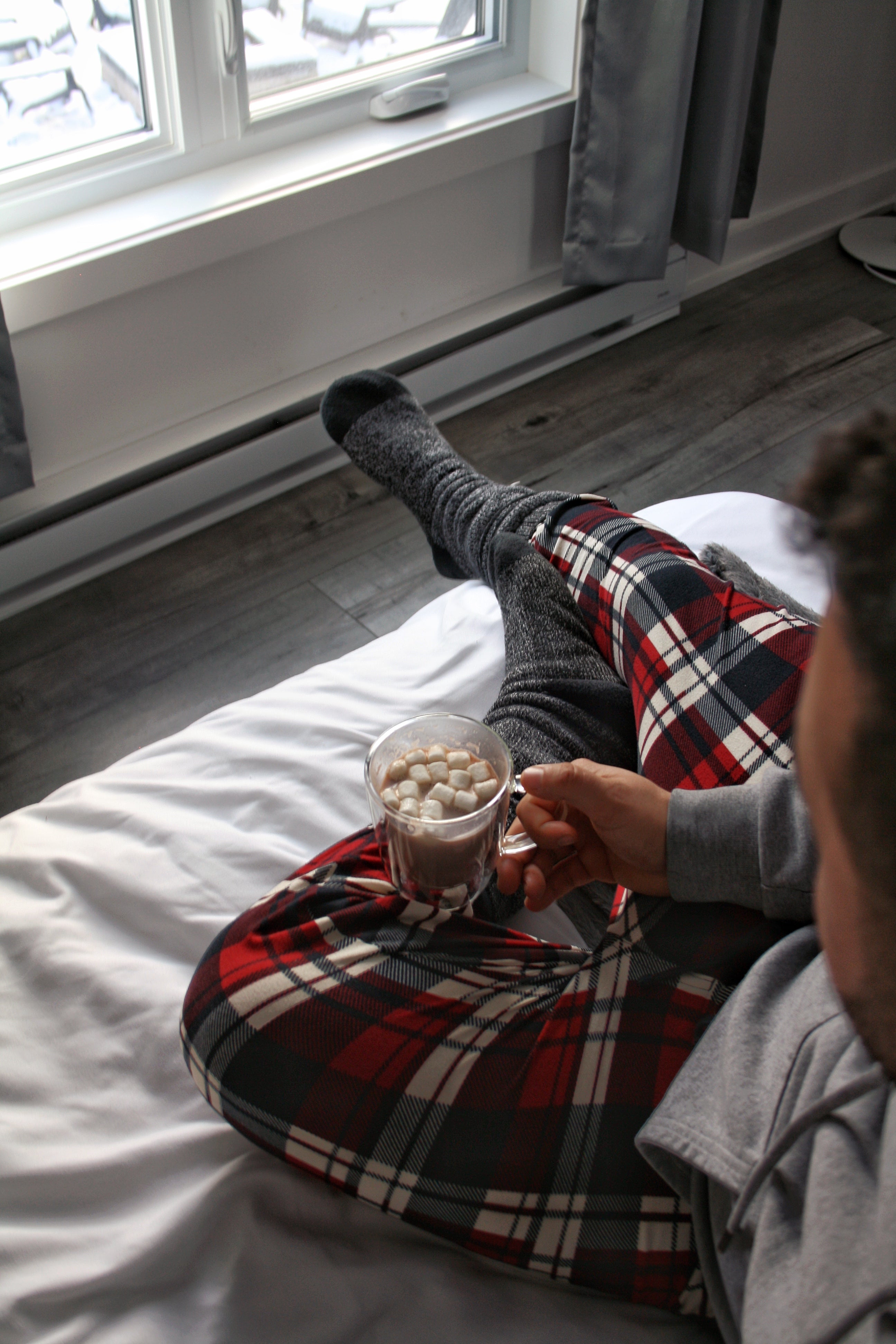 Man sitting on bed with thick socks on and hot chocolate